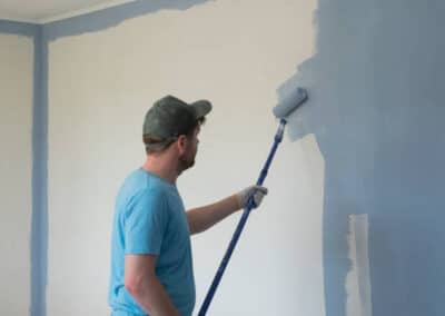 mature worker painting walls with a roller during flat renovation